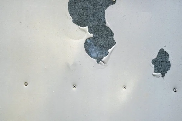 Metal sheet painted in white paint. Texture of peeling paint from a metal surface. White background with pieces of peeled paint.