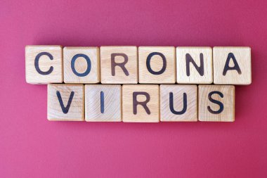 Koyu pembe arkaplanlı Corona virüsü. Covid-19 virüsünün salgını. Harfli tahta küpler..