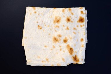 İnce pita yaprağı üst manzarayı katlamış. Siyah arka planda Pita ekmeği. Mayasız ince ev yapımı pide ekmeği.
