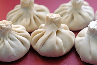 Plastik mutfak tahtasında ev yapımı khinkali. Çiğ Gürcü khinkalisi ve kuzu eti.