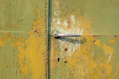 Alüminyum saplı, metal kapılı, yeşil bir kapı. Solmuş yeşil boyalı metal yüzey.