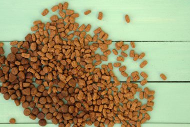 Kuru kedi maması üst görünümü. Yeşil ahşap arka planda kuru yem topakları. Hadım edilmiş kediler için farklı türde kuru yiyecekler. Dengeli evcil hayvan beslenmesi.