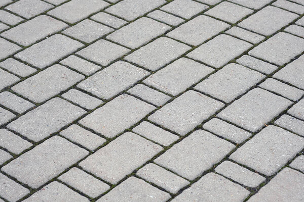 Texture of gray paving slabs. Diagonal line tiles for footpath background. Laying tiles on paths in a city park.