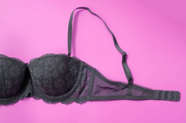 Pembe arka plan manzaralı gri sutyen. Bağlayıcı ve kayışlı dantel sütyen parçası. Güzel seksi iç çamaşırı, kadın cinselliği konsepti, meme sağlığı..