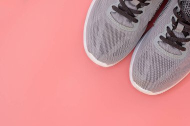 Pembe arka plan manzaralı gri spor ayakkabılar. Gri bağcıklı güzel örgü ayakkabılar. Spor ayakkabısı konsepti sabah koşusu, spor, aktif sağlıklı yaşam tarzı..