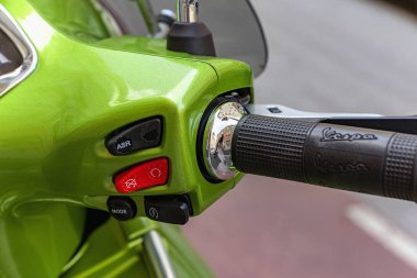Graz / Avusturya - Ağustos 2019: Otoparkta yeşil Vespa İtalyan tasarımı scooter. Düğmeli gidon. Scooter 'ın parçalarına şehrin yansıması. Kapat..
