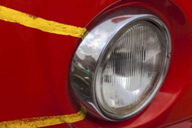 Sarı çizgili eski kırmızı bir arabanın farları.