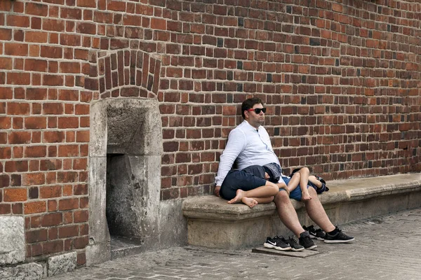 Krakow / Polen - augusti 2019: två pojkar trötta efter en promenad genom staden som sover i faderns knä — Stockfoto