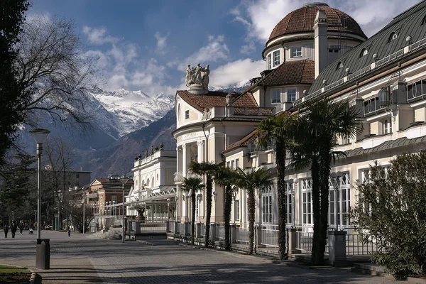 Merano / Olaszország - 2017. március: kilátás a Passer folyóval párhuzamos átjáróra, háttérben a Jugendstil Kurhaus épülettel és hófödte hegyekkel — Stock Fotó