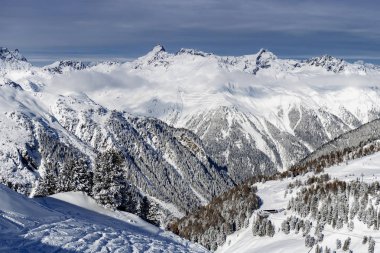 Kış manzarası; Mavi gökyüzü ve karla kaplı donmuş çam ağaçları ile kayak merkezinin üst manzarası.