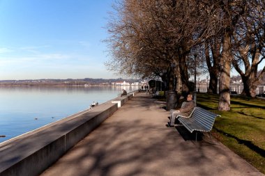 Begenz / Avusturya - Ocak 2020: İnsanlar Bregenz 'deki Constance Gölü' nün (Bodensee) kıyısında sıralarda dinleniyor ve yürüyorlar.