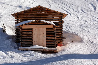 Kar arka planında kayak izleri olan Tyrolean Alplerinde saman depolamak için ahşap kulübe. Kış manzaralı bir dağ..