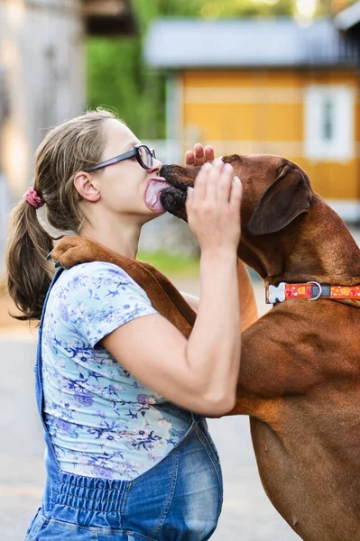 Zwanger meisje dragen bril omarmen en zoenen hond — Stockfoto