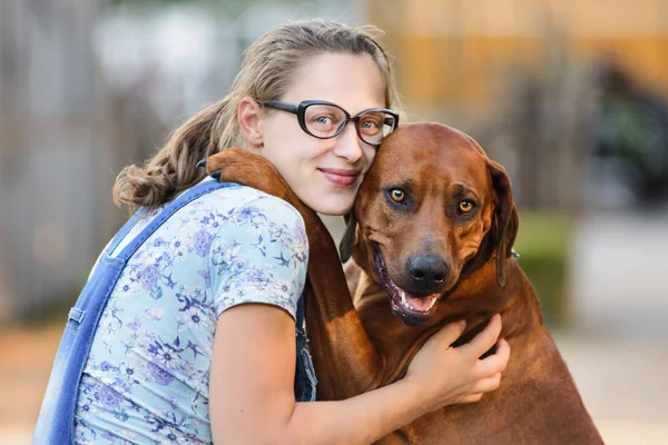 Zwanger meisje dragen bril omarmen en zoenen hond — Stockfoto