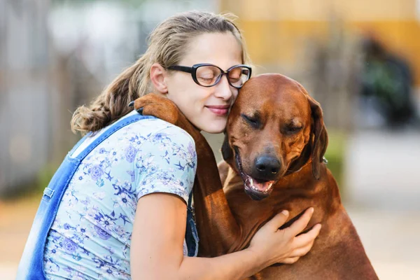 Zwanger meisje dragen bril omarmen en zoenen hond — Stockfoto