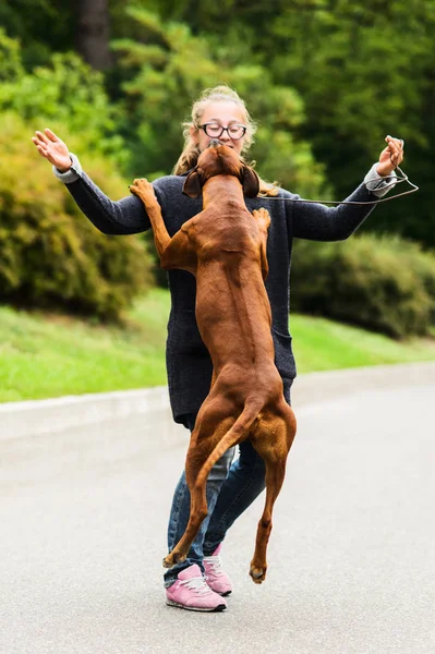 Gelukkig meisje spelen met haar vrolijke hond, springen, dansen — Stockfoto