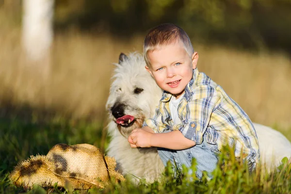 Щасливий усміхнений блондин хлопчик, що йде з другом собаки на фермі — стокове фото