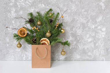 Ladin dallarının kış şenlikli buketi altın toplar, gri beton duvarlara karşı el sanatları paketi içinde koniler Xmas veya yeni yıl konsepti posta kartı, metin, tasarım için uzay şablonu kopyala