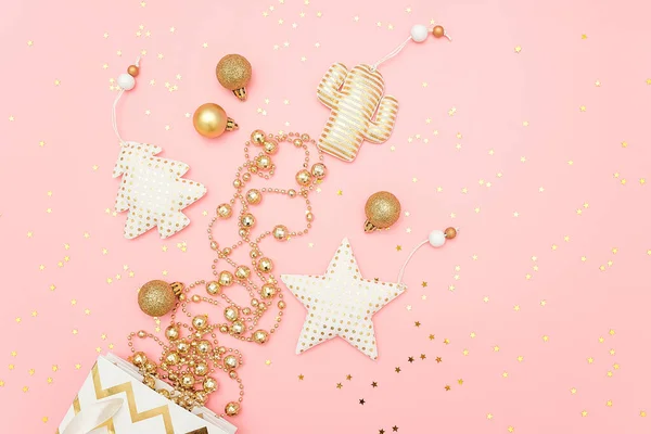 Різдвяні золоті прикраси вилітають з подарункової сумки та зірок конфетті на рожевому фоні з копіювальним простором. Веселого Різдва або З Новим Роком концепції. Шаблон верхнього перегляду для дизайну, листівки — стокове фото