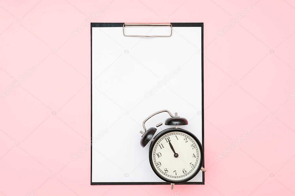 Clipboard with white blank paper and black alarm clock on pink background. Empty card for to-do list, schedule, plan and other text, design. Time, deadline or reminder concept. Flat lay Mockup