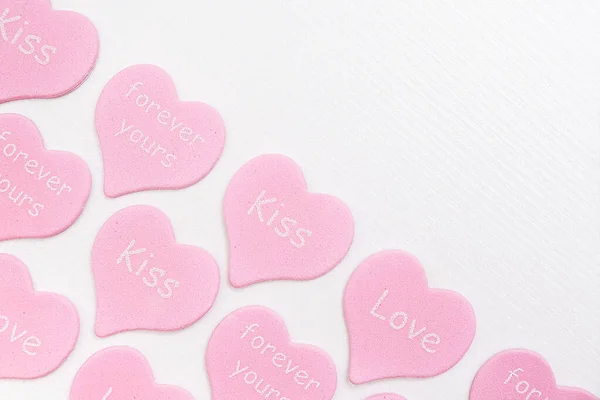 Fronteira corações cor-de-rosa com texto AMOR, KISS, FOREVER YOURS no fundo branco com espaço de cópia. Conceito do dia dos namorados. Presente para amante, confissão de amor. Vista superior Flat lay — Fotografia de Stock