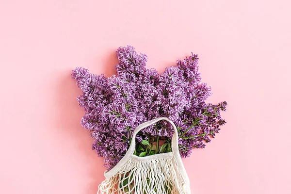 Hello spring. Bouquet of blooming lilac in reusable shopping eco mesh bag on pink background. Concept no plastic, zero waste. Copy space Top view Template for greeting card, postcard, invitation — Stock Photo, Image