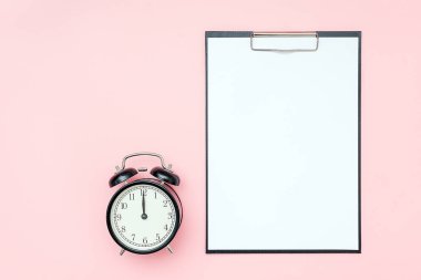 Beyaz boş kağıt ve pembe zemin üzerinde siyah alarm saati olan bir pano. Yapılacaklar listesi, program, plan ve diğer metinler için boş kart, tasarım. Zaman, mühlet ya da hatırlatma konsepti. Düz yatış Model