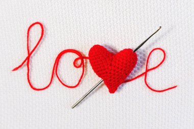 Sevgililer günü, düğün arkaplanı. Tığ işi kanca, beyaz örülmüş arkaplandaki ipliklerden çıkan aşk okuna benzer şekilde kırmızı bir kalbi delip geçti. Tasarım şablonu, sevgililer günü kartı, davet