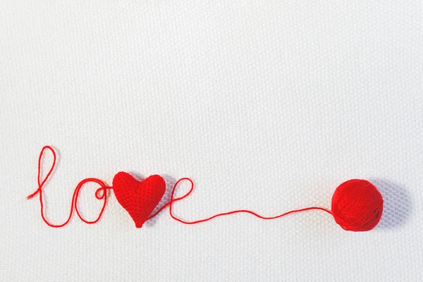 San Valentino o sfondo di nozze. Cuore di volume rosso lavorato a maglia nella parola amore e palla di filo su sfondo bianco lavorato a maglia. Modello per design, biglietto da visita, invito. Copia spazio Vista dall'alto — Foto Stock