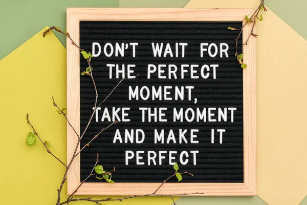 Не ждите идеального момента, найдите момент и сделайте его идеальным. Мотивационная цитата на раме доски букв и ветвях весенних деревьев на зеленом фоне — стоковое фото