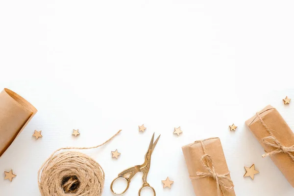 Set of materials for packing holiday gifts. Kraft paper, jute twine, scissors, boxes on white background. Holiday zero waste and eco-friendry concept. Top view Flat lay Copy space.