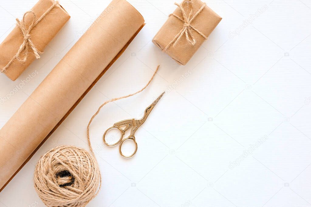 Set of materials for packing holiday gifts. Kraft paper, jute twine, scissors, boxes on white background. Holiday zero waste and eco-friendry concept. Top view Flat lay Copy space.
