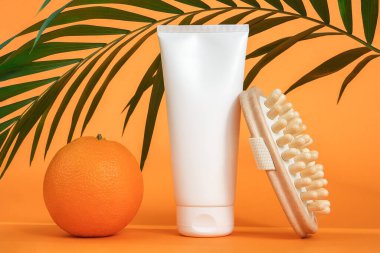 Beyaz boş kozmetik krem veya vücut losyonu, portakal meyvesi, ahşap anti-selülit masaj aleti ve yeşil palmiye dalı. Selülitlere karşı kavramsal mücadele. Model Ön Görünüm.
