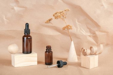 Serum, esaslı yağlar ya da kahverengi cam şişedeki sıvı kolajen, pipette, ahşap geometrik şekiller ve bej kağıtta kurumuş çiçekler. Doğal Organik Spa Kozmetik Güzellik Konsepti.