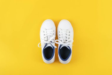 Beyaz spor ayakkabıları, sarı arka planda ayakkabı bağcığı olan spor ayakkabıları. Spor yaşam tarzı konsepti Üst Görünüm Düz Kopya Alanı.