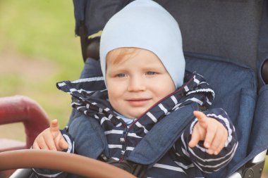 Bekar bir anne, göl kenarında doğal sarı ve beyaz arka planlı bir çocuğu taşıyıp kucaklıyor.