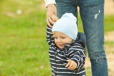 Bekar bir anne, göl kenarında doğal sarı ve beyaz arka planlı bir çocuğu taşıyıp kucaklıyor.