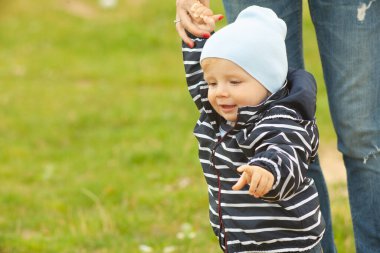 Bekar bir anne, göl kenarında doğal sarı ve beyaz arka planlı bir çocuğu taşıyıp kucaklıyor.