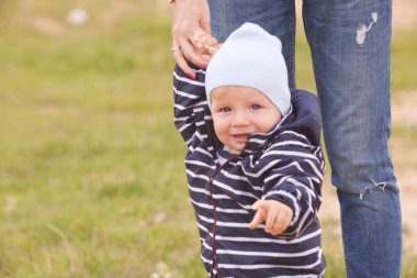 Bekar bir anne, göl kenarında doğal sarı ve beyaz arka planlı bir çocuğu taşıyıp kucaklıyor.