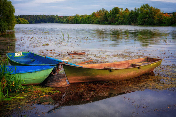 Beautiful morning landscape with a boat on the lake at the sunrise through the reed