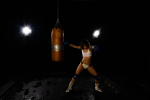 Young sexy Woman boxer. Martial arts or self defence. Sport boxer woman in boxing gloves makes a kick . Fitness girl training kick boxing. Boxing training on ring. Confident athlete woman in boxing gloves. Sport and fitness. Silhuette on black backgr