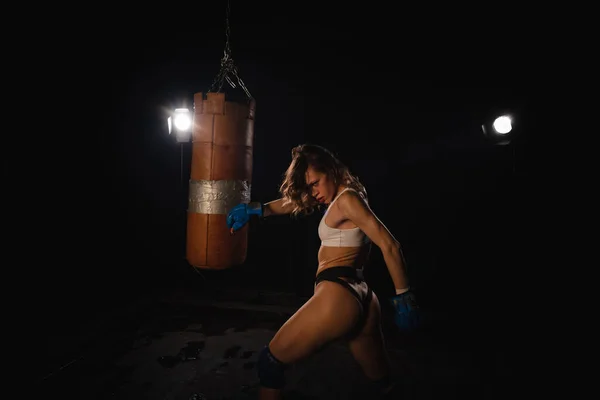 Young sexy Woman boxer. Martial arts or self defence. Sport boxer woman in boxing gloves makes a kick . Fitness girl training kick boxing. Boxing training on ring. Confident athlete woman in boxing gloves. Sport and fitness. Silhuette on black backgr