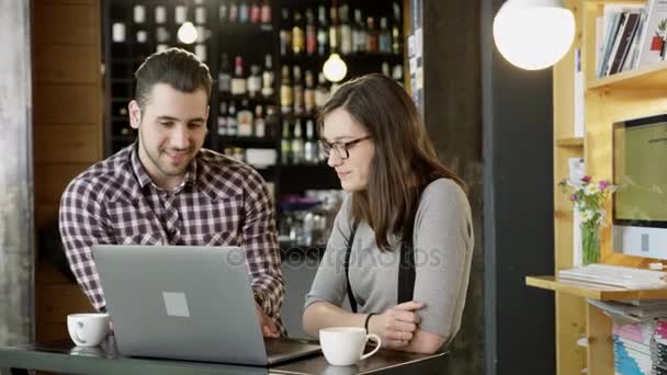 Jonge Man en vrouw, drinken koffie en werken op een Laptop bij de Bar van de koffie glimlachend Project Online businessconcept bespreken langzaam Motion Shot op Red epische 8k — Stockvideo