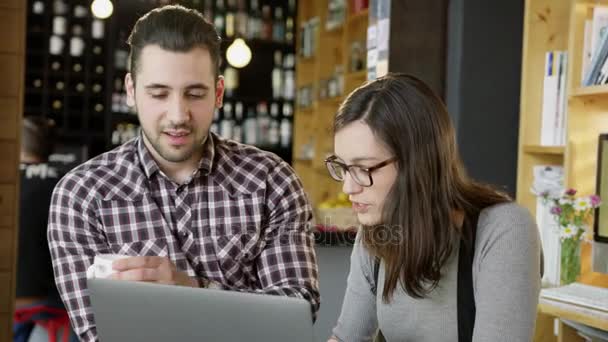 Homem e mulher discutindo projeto olhando para laptop na cafetaria sorrindo trabalho em equipe on-line conceito de negócios lento movimento tiro no épico vermelho 8K — Vídeo de Stock