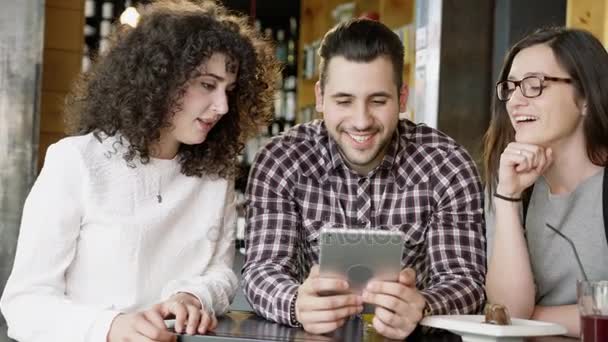 Diverso grupo de jóvenes amigos sosteniendo una tableta riéndose en la cafetería estudiantes estudiando mirando videos divertidos de temas de cámara lenta tiro en rojo épica 8K — Vídeo de stock