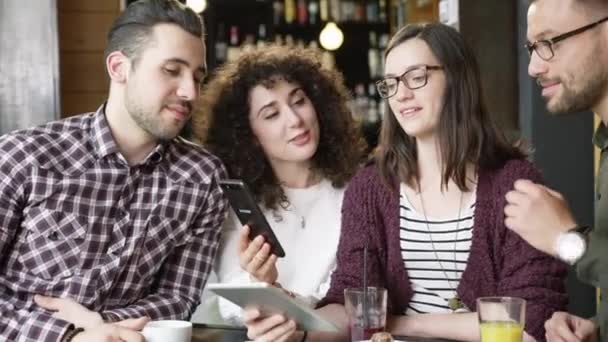 Genç ve güzel insanların bir Smartphone eğlenerek içme kahve Cafe yavaş hareket, gülümseyen Internet Meme videoları paylaşım bakarak ateş kırmızı Epic 8k — Stok video