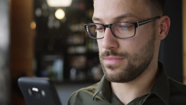 Homem bonito com óculos usando telefone inteligente em uma barra de café 3G 4G Wi-Fi Conexão Tecnologia Conceito Slow Motion Shot em vermelho épico 8K — Vídeo de Stock