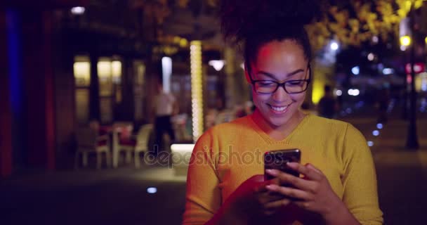 Feliz rizado urbano mujer mensajes de texto en el teléfono usando viaje aplicación moderna tecnología al aire libre cámara lenta rojo épica 8k — Vídeo de stock