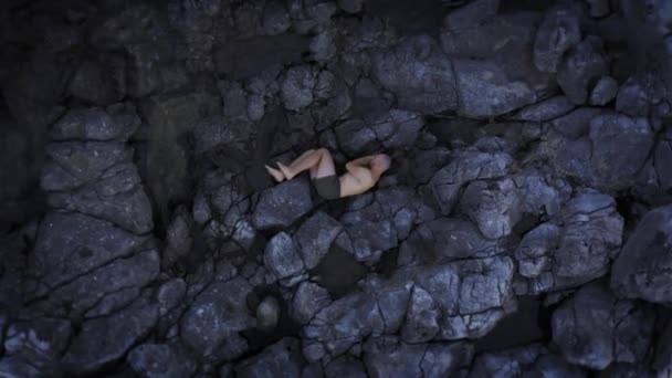 Dépression et solitude Jeune homme en posture foetale allongé impuissant sur des rochers de mer Défaillance d'une falaise Douleur Péché Concept Vue du dessus — Video