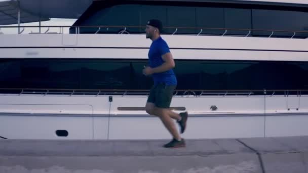 Joven atleta hombre corriendo corriendo corriendo por yates de lujo muelle al atardecer saludable estilo de vida determinación éxito concepto — Vídeos de Stock